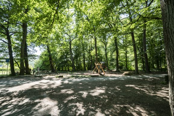 Blick über den großzügig angelegten Spielbereich mit Schaukel, Seilbahn, Sandkasten